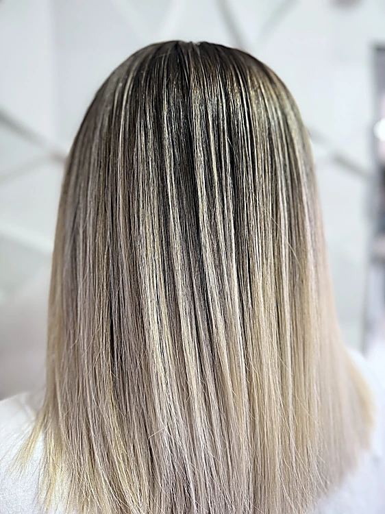 Corte recto con luces ceniza, de espaldas, sobre fondo gris claro