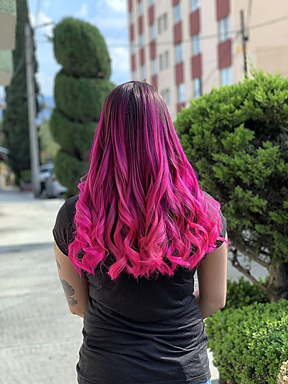 Ondas con puntas fucsia sobre castaño, de espaldas, en la calle